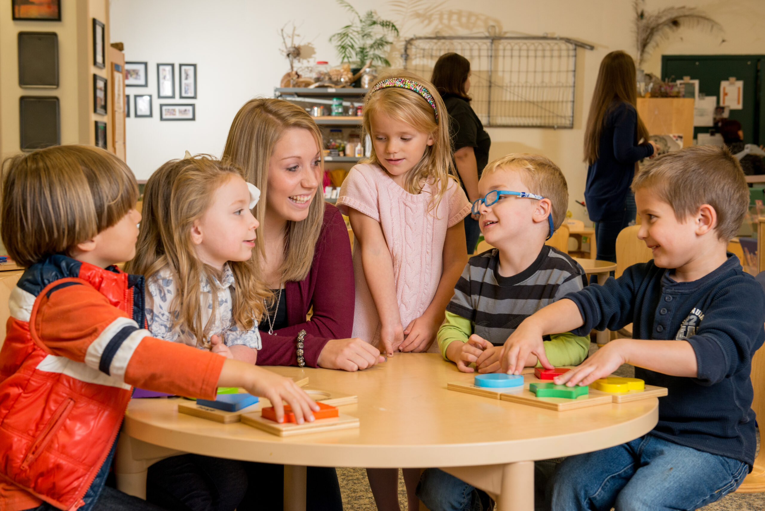 Preschool children sitting around a table with a teacher.